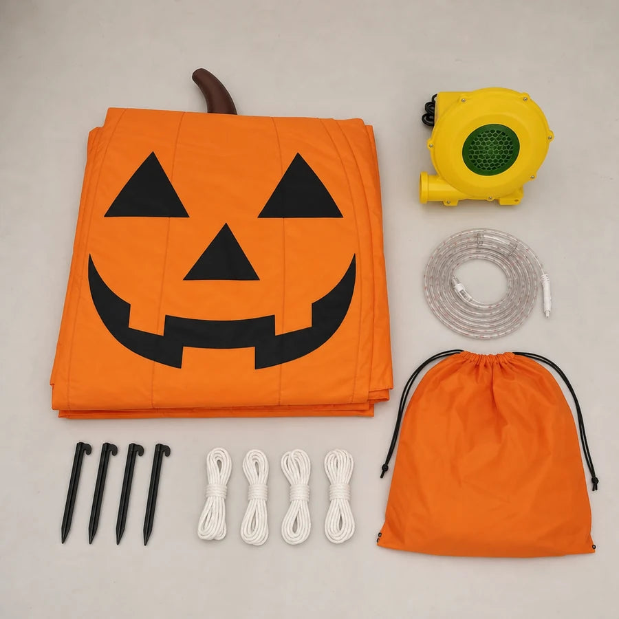 Overhead flat-lay of the pumpkin's folded fabric, blower, LED strip, stakes, ropes and carry bag