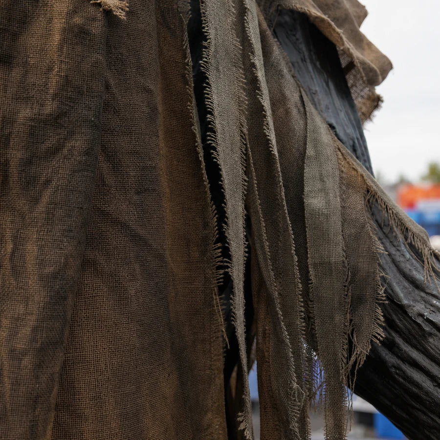 Macro of the tattered robe fabric showing frayed torn edges and weathered cloth texture