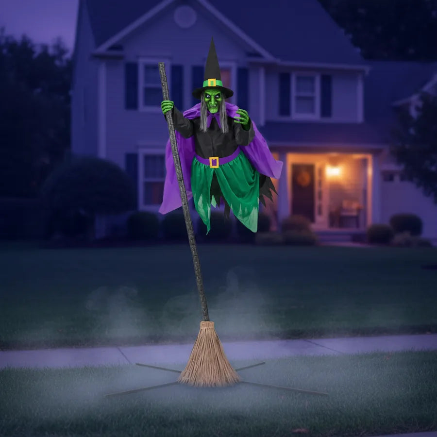 Gravesend 12 ft Witch Animatronic set up on a suburban front lawn at night, lit against the house