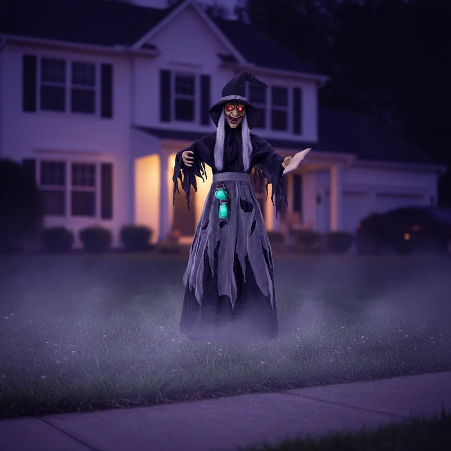 Ravenmoor Witch Animatronic set up on a suburban front lawn at night, lit against the house