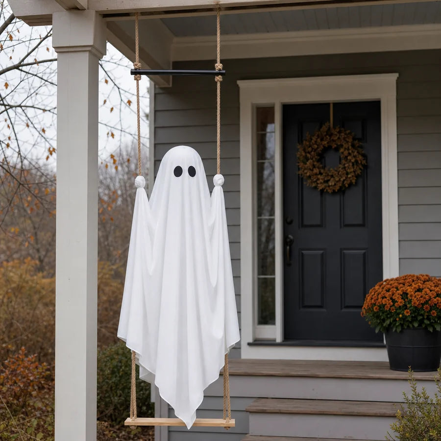 The ghost hanging unlit from a porch beam on an overcast afternoon, plain white cloth beside a dark front door