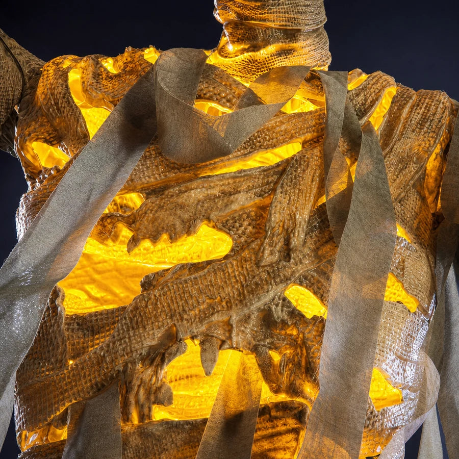 Close-up of the wrapped chest with amber light glowing through gaps in the cloth