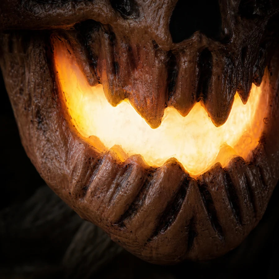 Macro of the carved mouth lit bright amber from inside, teeth catching the glow