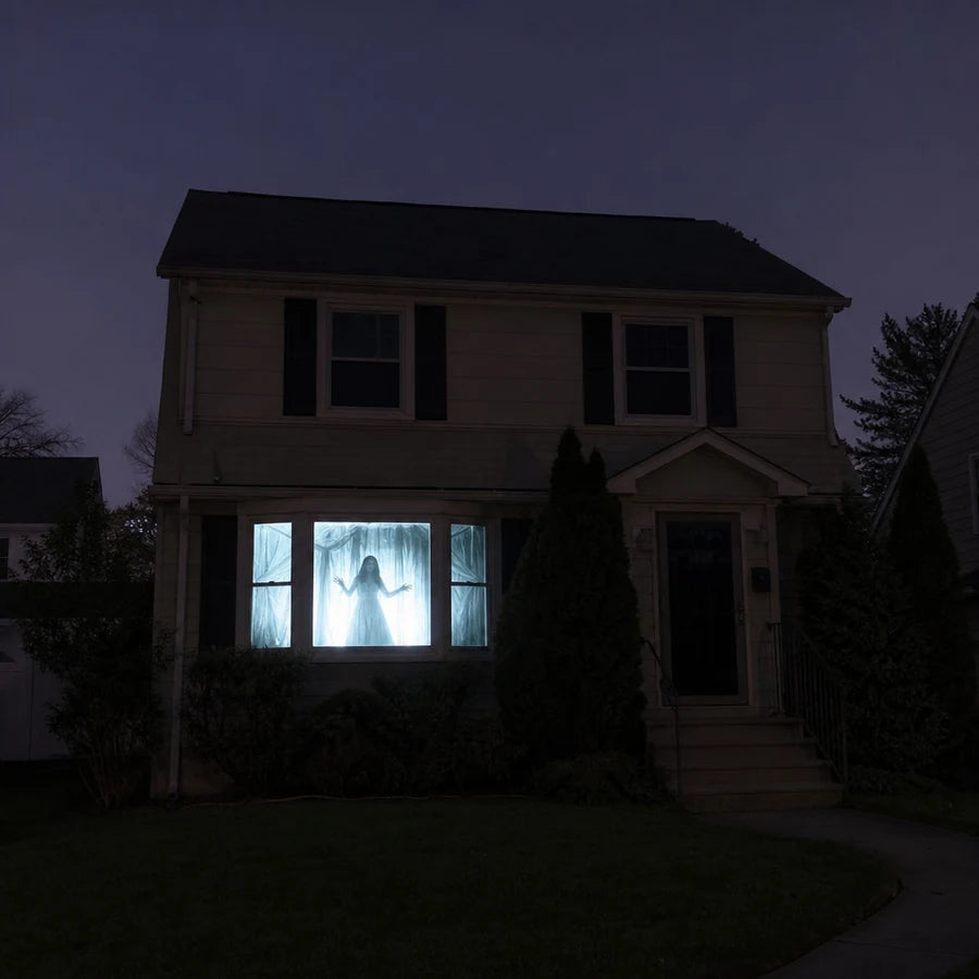 A house at night seen from the yard, its front window glowing with a pale haunted scene