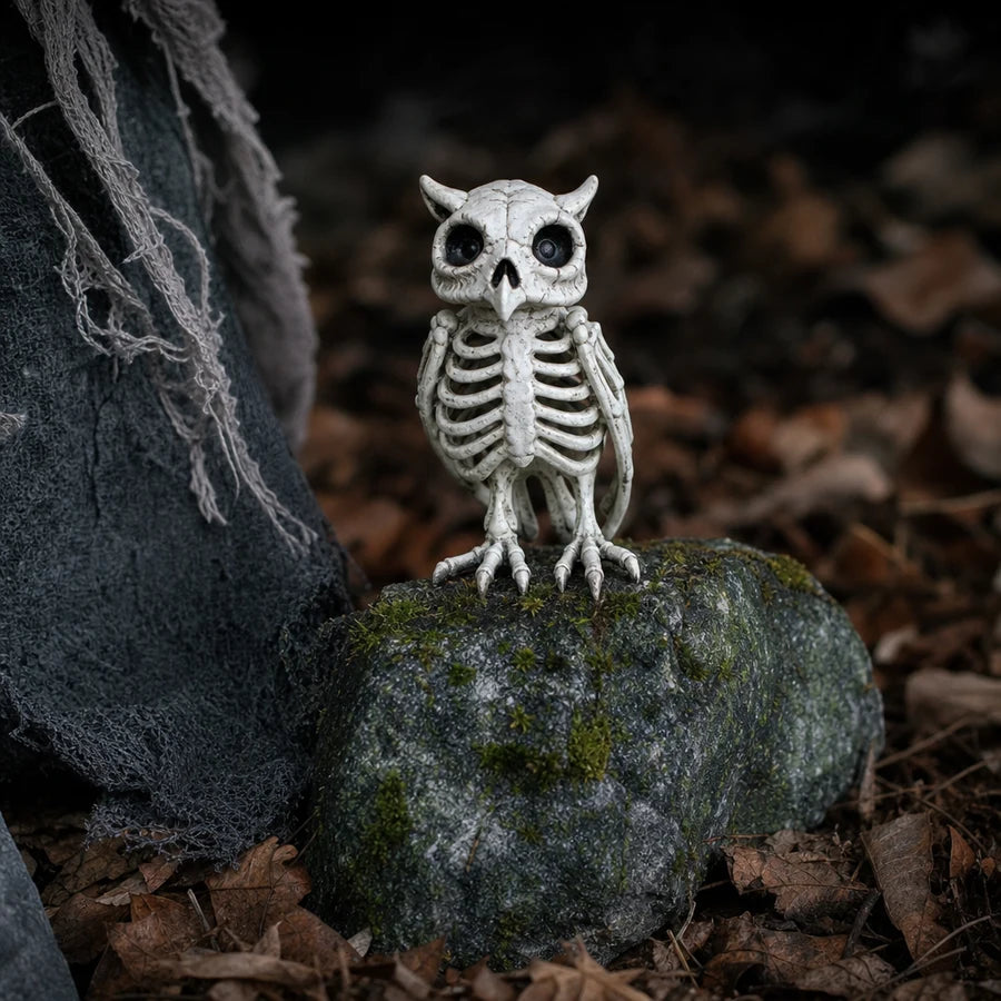 A small skeleton owl figure perched on a stone by her feet